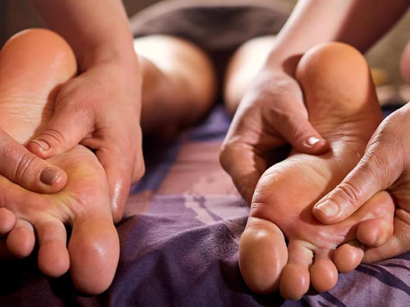 Massage in four hands on feet in the spa salon.