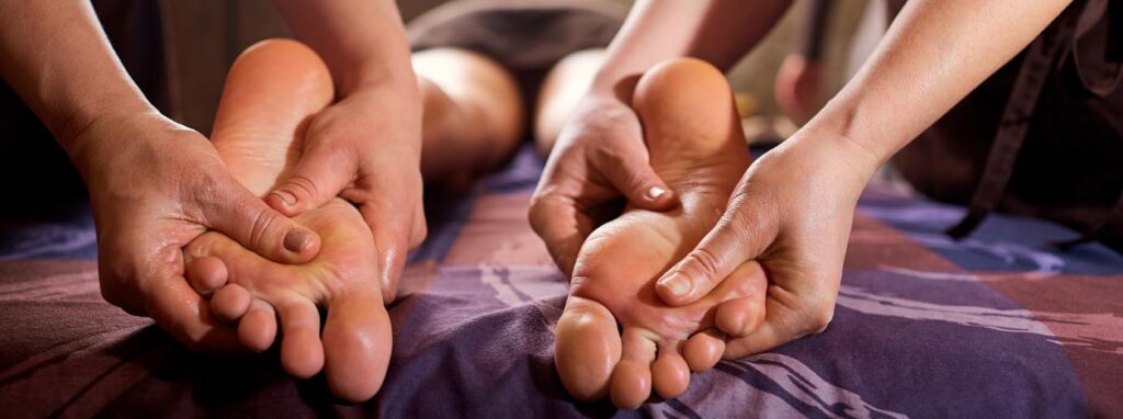 Massage in four hands on feet in the spa salon.